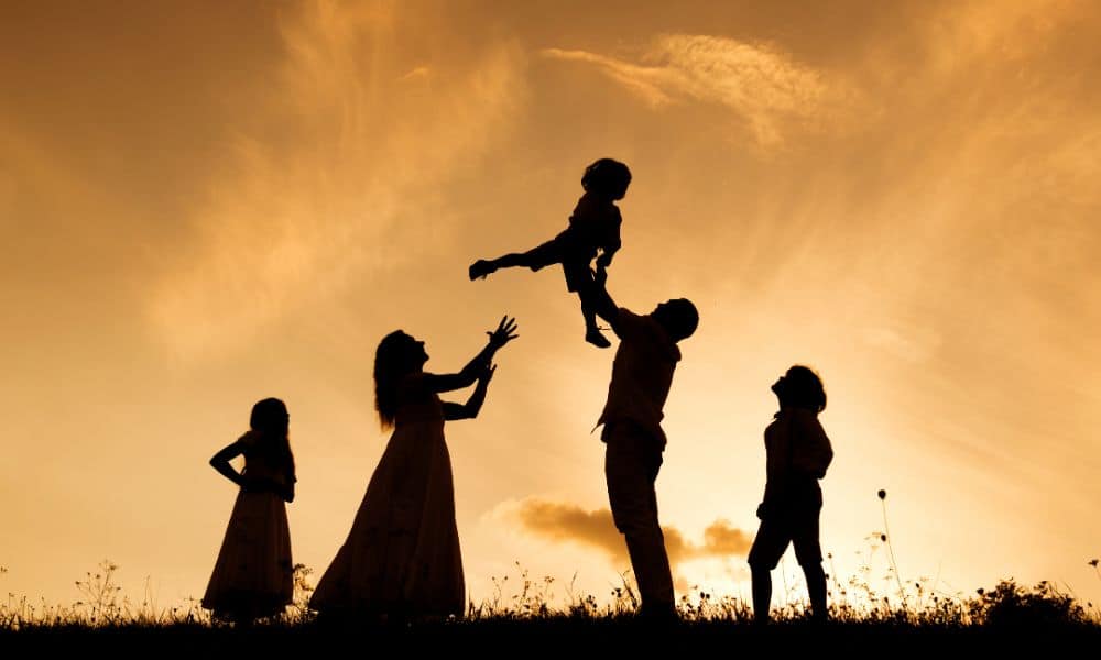 Silhouette of a young family outside having fun against a sunset sky
